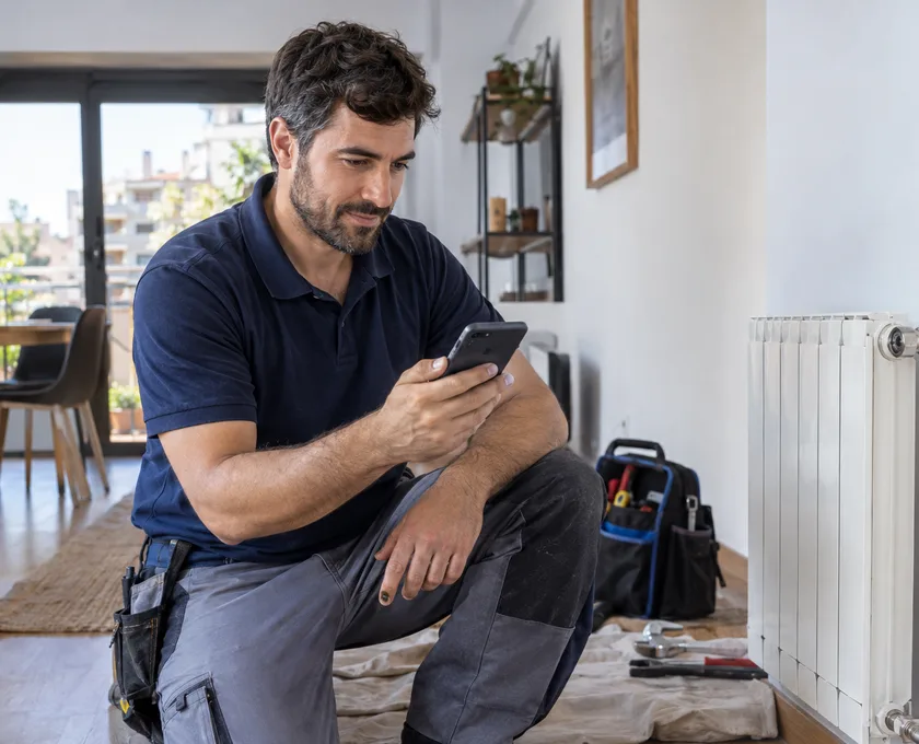 Profesional del hogar atendiendo una solicitud desde su teléfono durante un trabajo